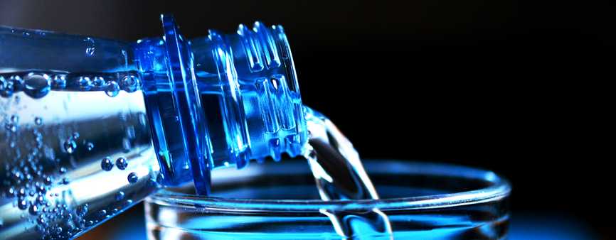 Photo of a bottle of water being poured into a glass.