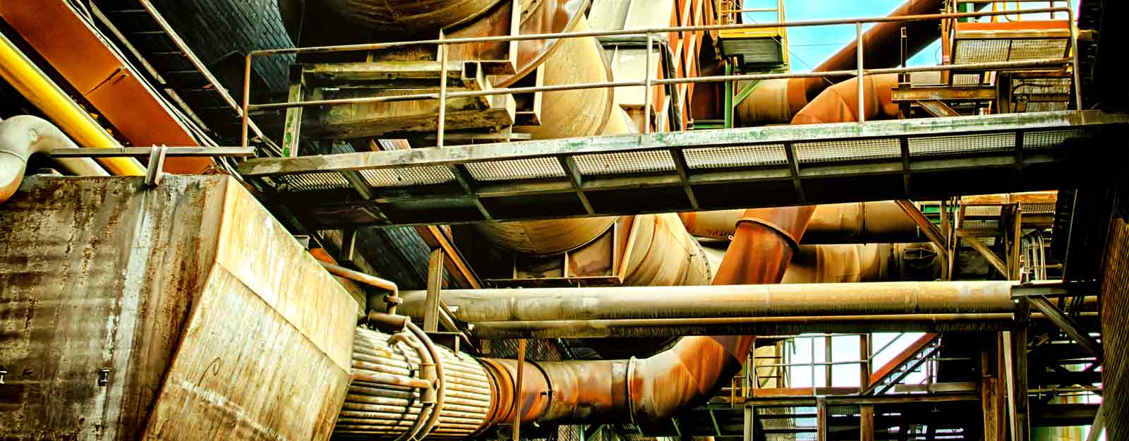 Photo of walkways and pipes on the outside of an industrial building.